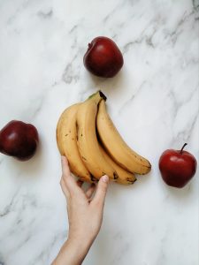 a person holding a bunch of bananas and apples